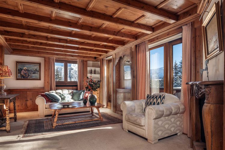 Private sitting area at Chalet Margaux with a cream sofa and armchair, traditional timber interiors, decorative furnishings and mountain views.