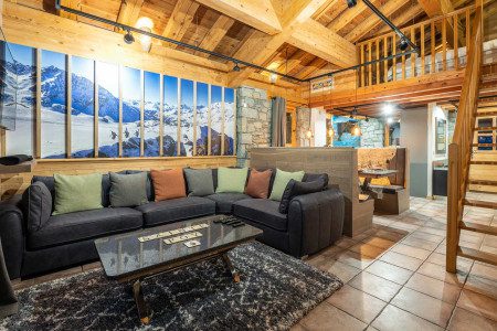 Lounge area at Apartment Les Balmes with a large corner sofa, alpine decor, exposed beams and mezzanine above.