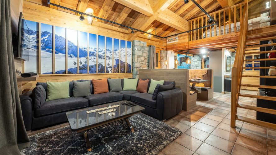 Lounge area at Apartment Les Balmes with a large corner sofa, alpine decor, exposed beams and mezzanine above.