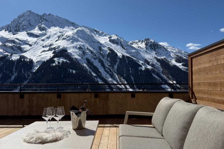 Drinks set on the terrace at Apartment Panorama with outdoor seating and panoramic views of snow-covered alpine mountains.