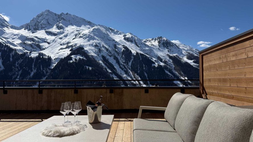 Drinks set on the terrace at Apartment Panorama with outdoor seating and panoramic views of snow-covered alpine mountains.