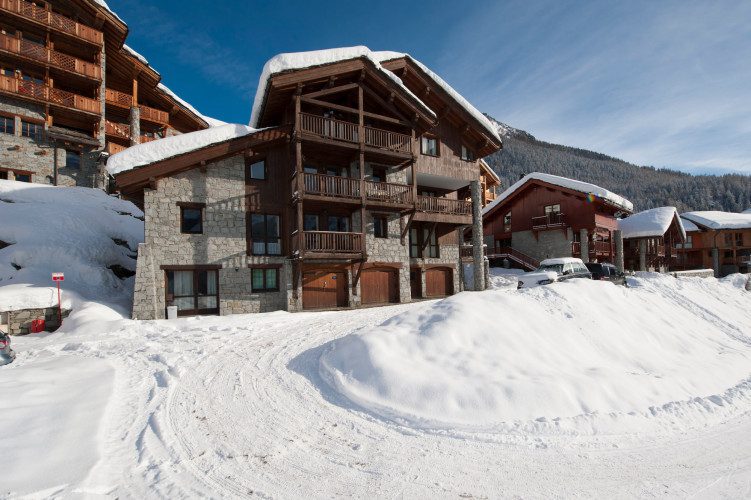Exterior of Chalet Cheval Blanc surrounded by deep snow, with traditional stone and timber architecture and alpine balconies.