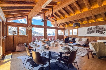 Bright dining space at Chalet Snoopy with a large table, exposed timber beams, comfortable lounge seating and panoramic mountain views.