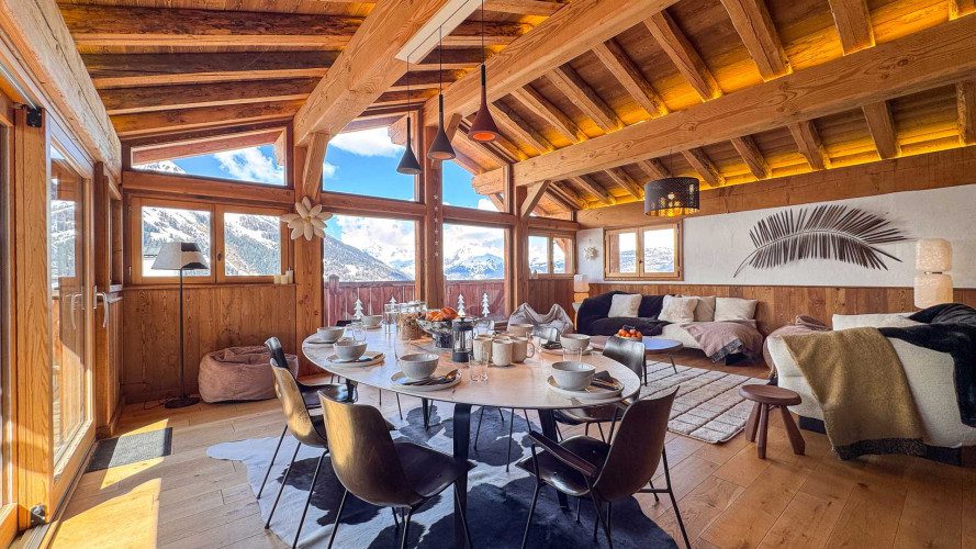 Bright dining space at Chalet Snoopy with a large table, exposed timber beams, comfortable lounge seating and panoramic mountain views.