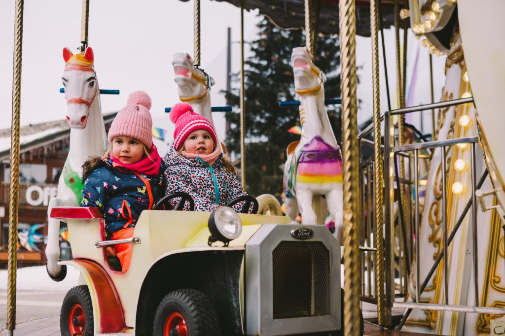 Children sitting in a car on a fairground ride in Morzine at Christmas