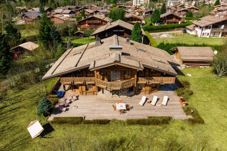 Bird’s-eye view of Chalet Panorama showing the large wooden terrace, garden, outdoor seating and surrounding alpine chalets.