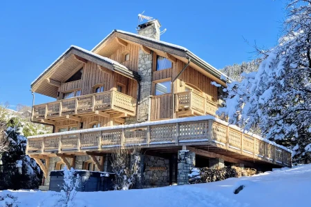 Exterior of Chalet Bellevue in the snow with timber balconies and stone detailing