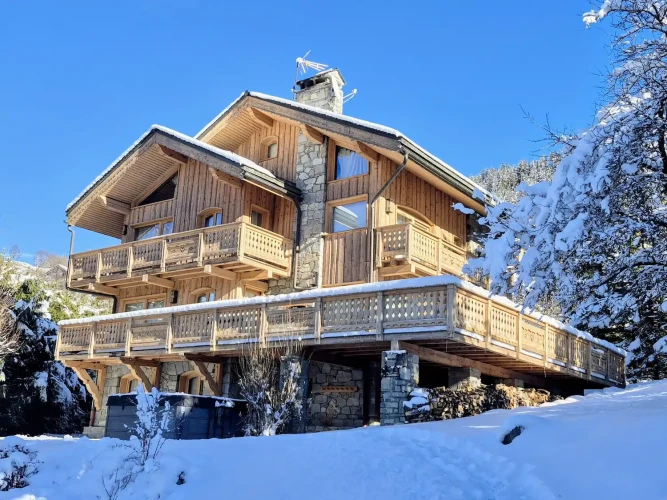 Exterior of Chalet Bellevue in the snow with timber balconies and stone detailing