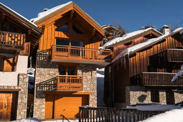 Exterior of Chalet Meru with timber balconies, stone walls and snow-covered roof