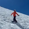 Snowboarder descending a snowy slope in Chamonix beneath a clear blue alpine sky.